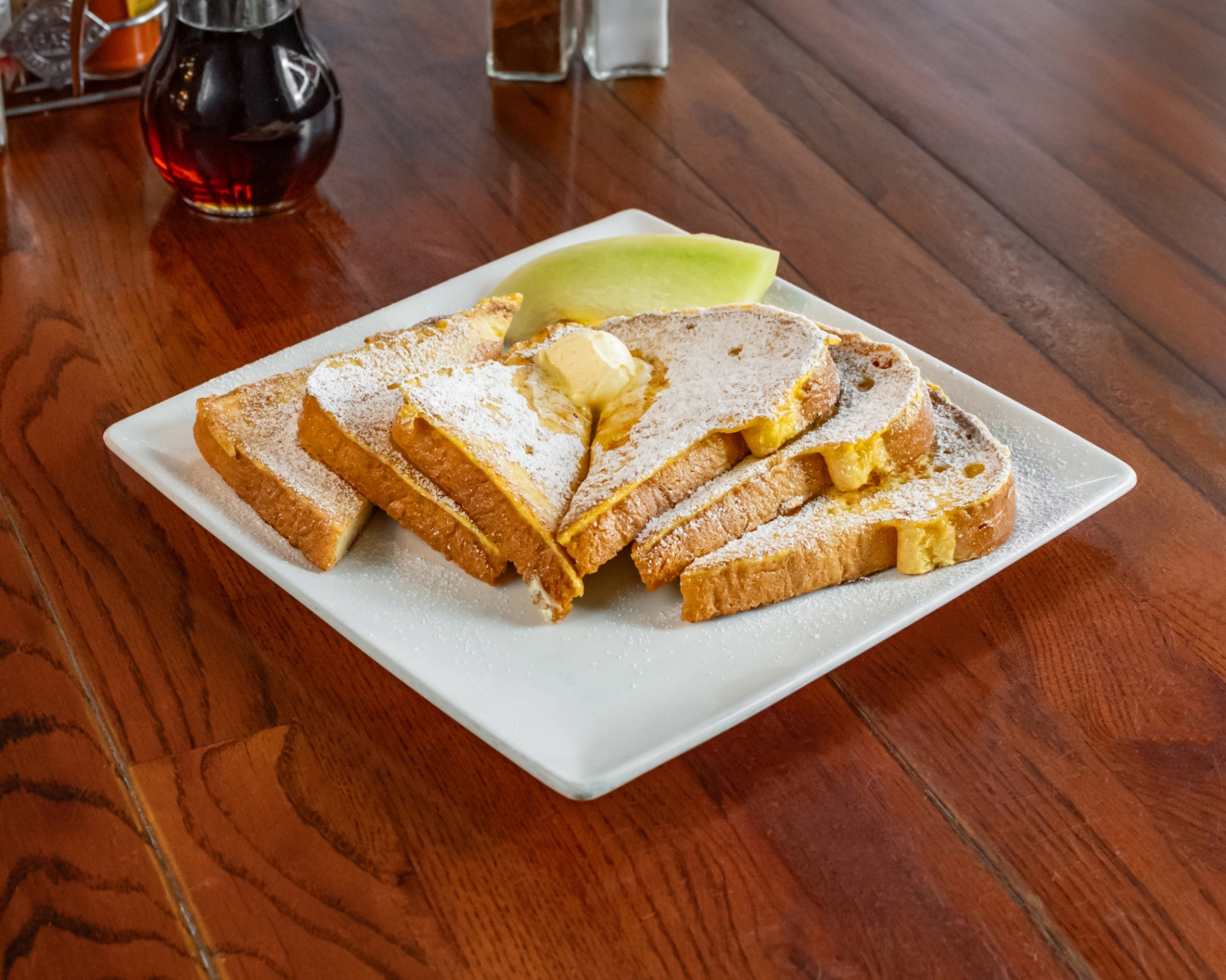 Powdered sugar French toast with butter and thick-cut bacon